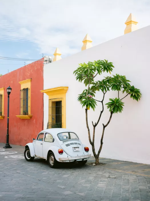 Zwart, Raisa: Pastellfarbener Volkswagen Beetle in den Straßen von Oaxaca, Mexiko